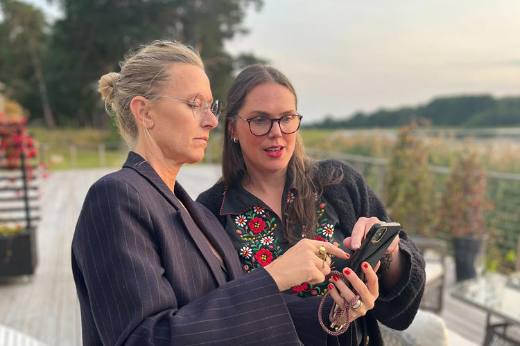 Två tjejer tittar och pekar på en telefon