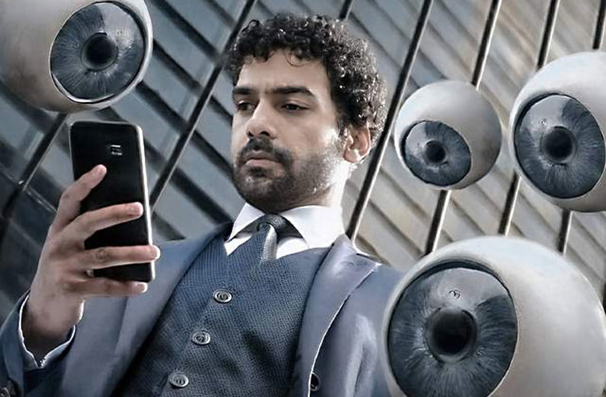 Man tittar i telefon med massa lösa ögon som tittar över axeln
