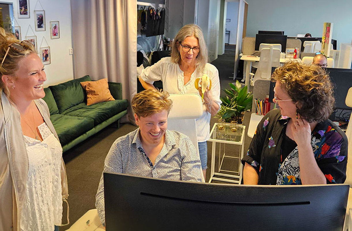 Glada kollegor som samlats runt en datorskärm