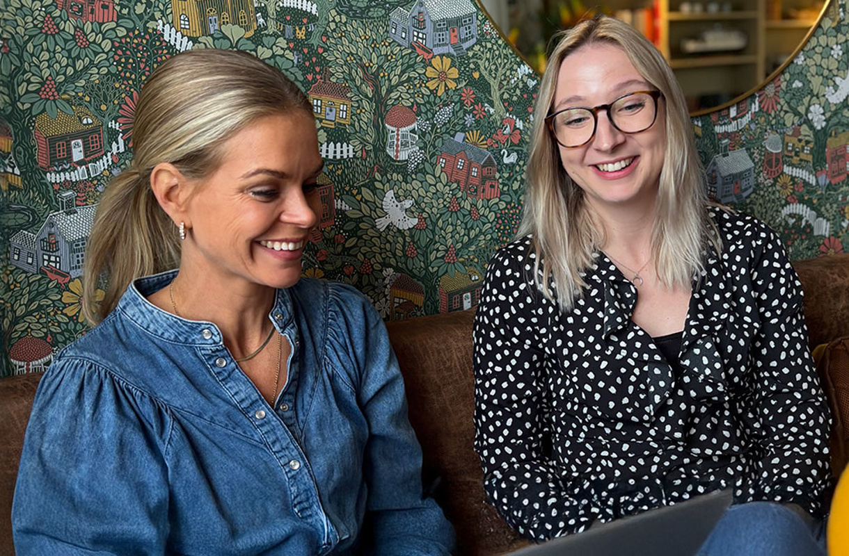 Ellen och Frida  på Lexicon Interactive leende i soffa framför grön och blommig tapet