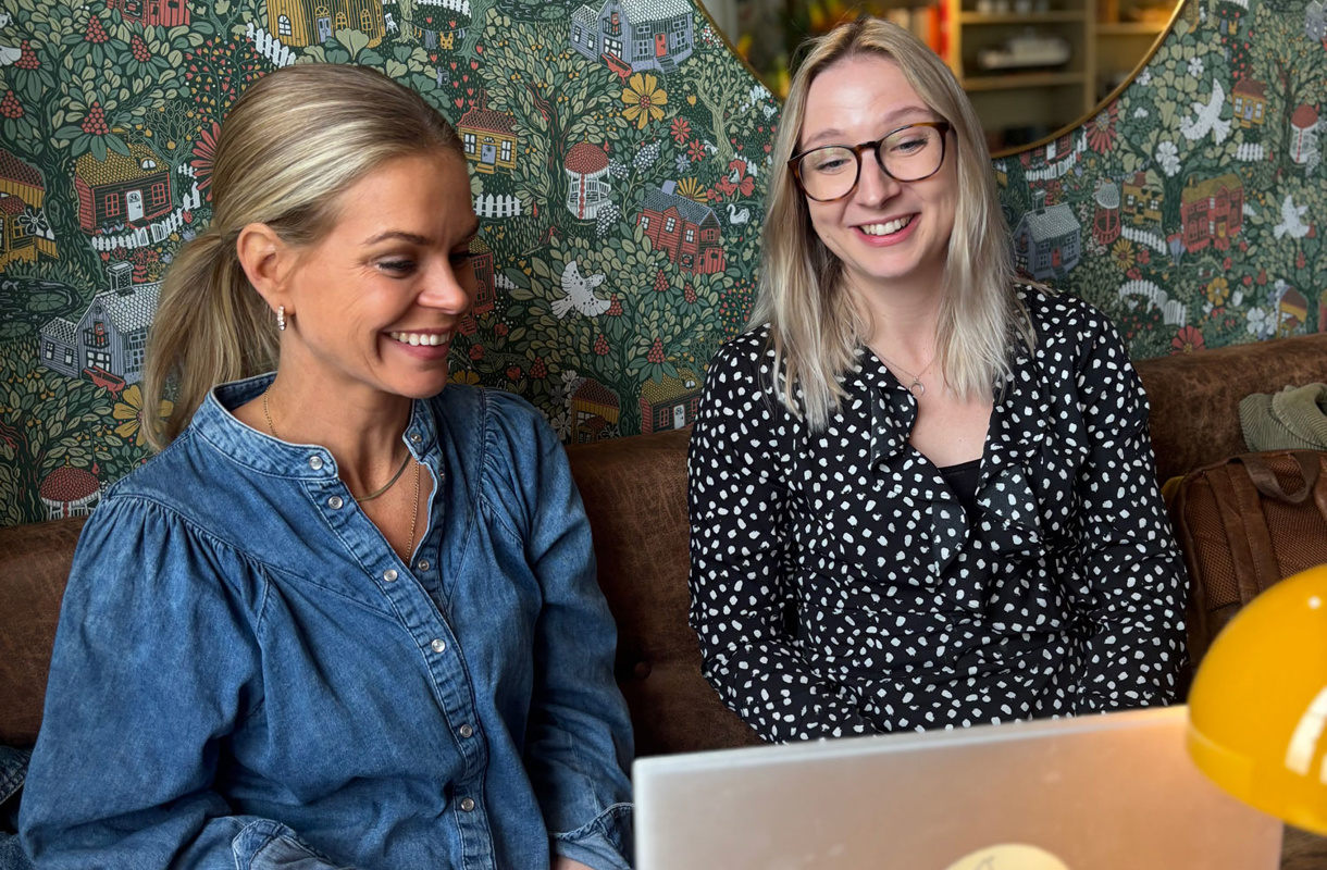 Ellen och Frida  på Lexicon Interactive leende i soffa framför grön och blommig tapet
