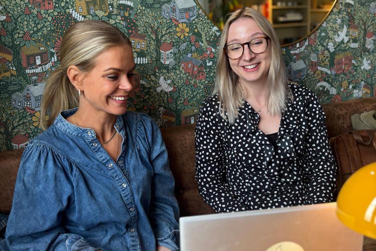 Ellen och Frida på Lexicon Interactive leende i soffa framför grön och blommig tapet