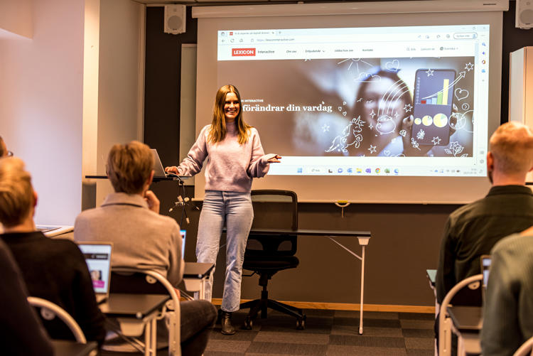 Talar framför åhörare, Lexicon Interactives hemsida på storskärm bakom