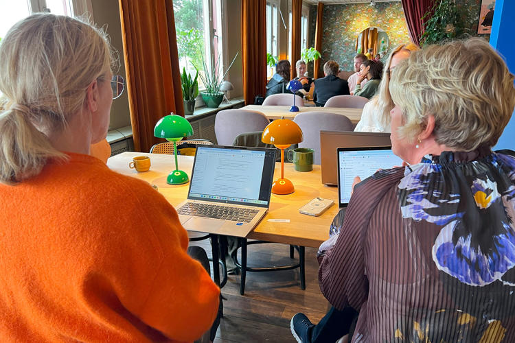 Människor runt bord i kafémiljö med datorer