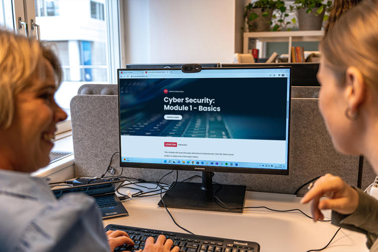 Två tjejer tittar i en dator med kursen Cyber Security öppen