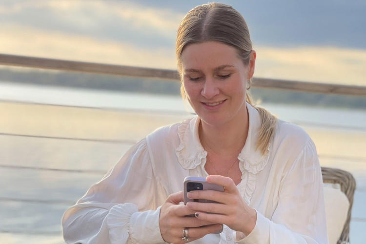 Ebba på Lexicon Interactive sitter ute och tittar leende i mobilen