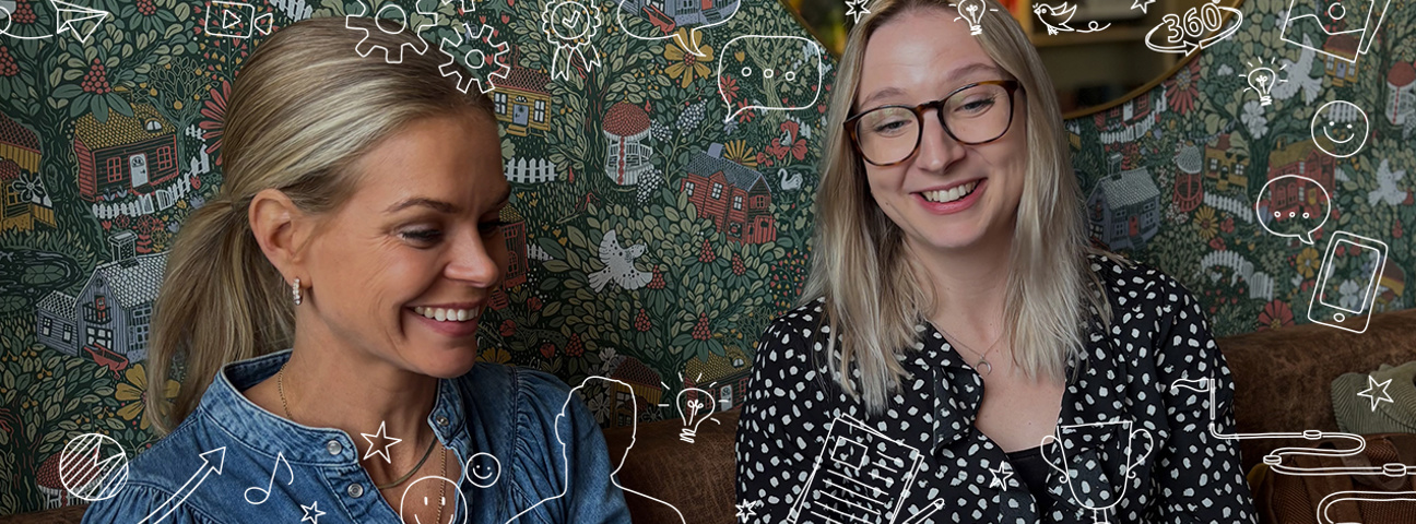 Ellen och Frida  på Lexicon Interactive leende i soffa framför grön och blommig tapet